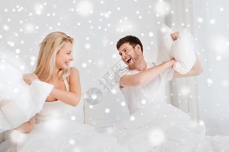 人们,家庭,睡觉时间趣的幸福的夫妇雪地上的床上打枕头战背景