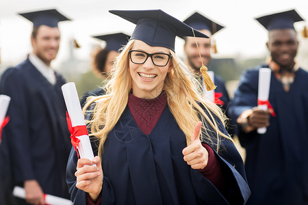 教育毕业手势人的群快乐的国际学生穿着灰浆板学士服,毕业证书竖大拇指璃杯高清图片素材