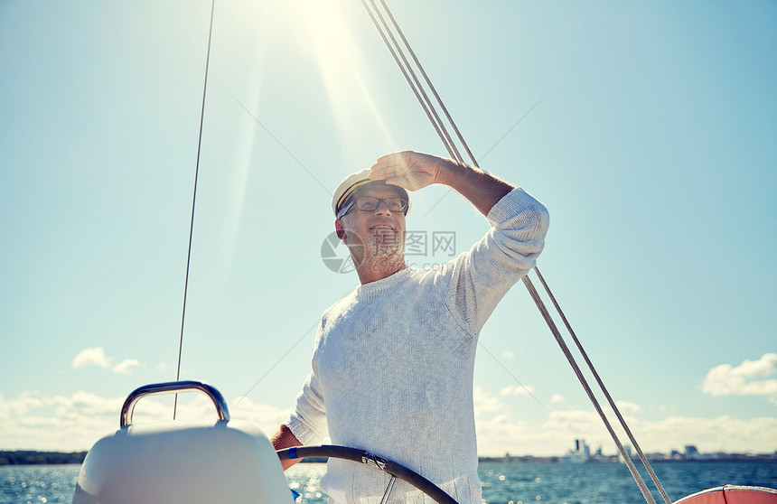 航海,龄,旅游,旅游人的快乐的老人戴着船长帽子方向盘上,看着遥远的帆船游艇漂浮海上图片