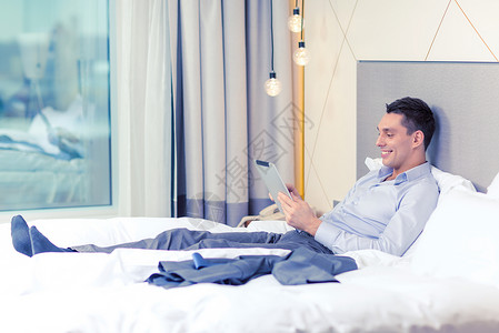 酒店wifi商业,技术,互联网酒店快乐的商人与平板电脑电脑躺酒店床上背景