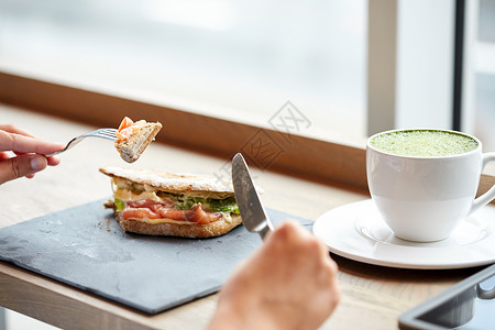 食物,晚餐人们的女人吃鲑鱼帕尼尼三明治与杯抹茶绿茶铁餐厅图片