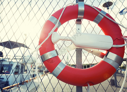 红白救生圈航行,安全生命救援救生圈悬挂码头停泊的船只上的栅栏上背景