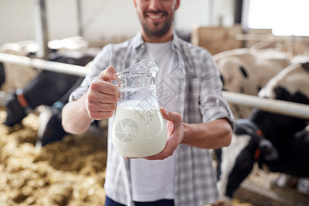 农业农业人畜牧业的快乐的微笑轻人农民,奶牛场的牛棚里放牛奶背景图片