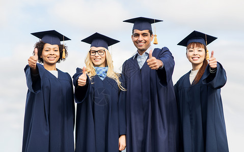 教育毕业手势人的群快乐的国际学生穿着灰浆板学士服户外竖大拇指学校高清图片素材
