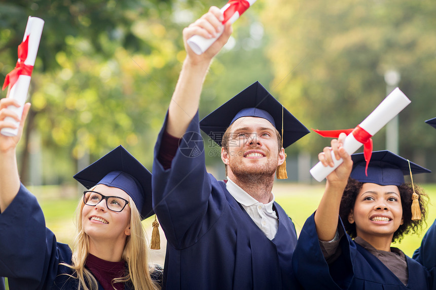 教育毕业人的群快乐的国际学生穿着灰浆板学士服,毕业证书庆祝成功图片