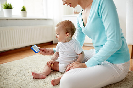 家庭,技术,孩子父母的亲密的快乐微笑的轻母亲向家里的小婴儿展示智能手机图片