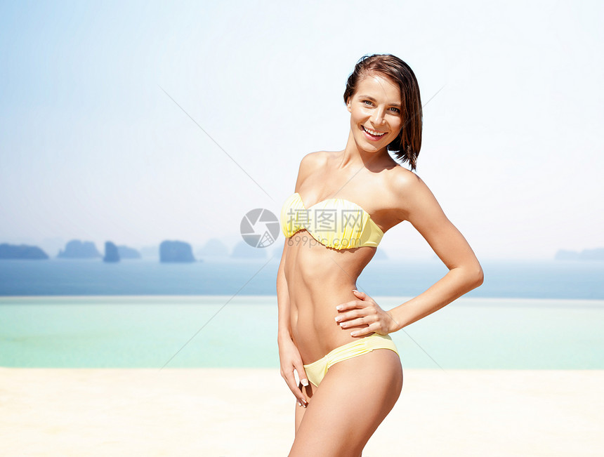 人们,暑假,假期旅行的快乐的轻女人摆着比基尼泳衣,双手越过大海无限的边缘游泳池背景快乐的女人穿着比基尼泳衣边缘图片
