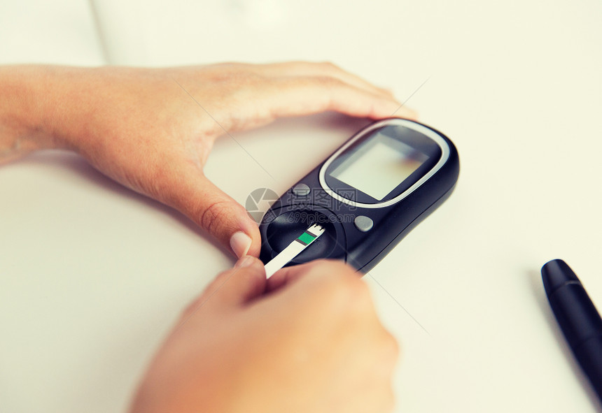 药物,糖尿病,血糖,保健人的用血糖仪密切妇女的手,并家里测试条纹检查血糖水平用血糖仪妇女进行血液测试图片