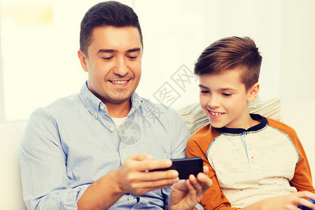 休闲,技术,家庭人的快乐的父子与智能手机短信家玩游戏快乐的父子智能手机家图片