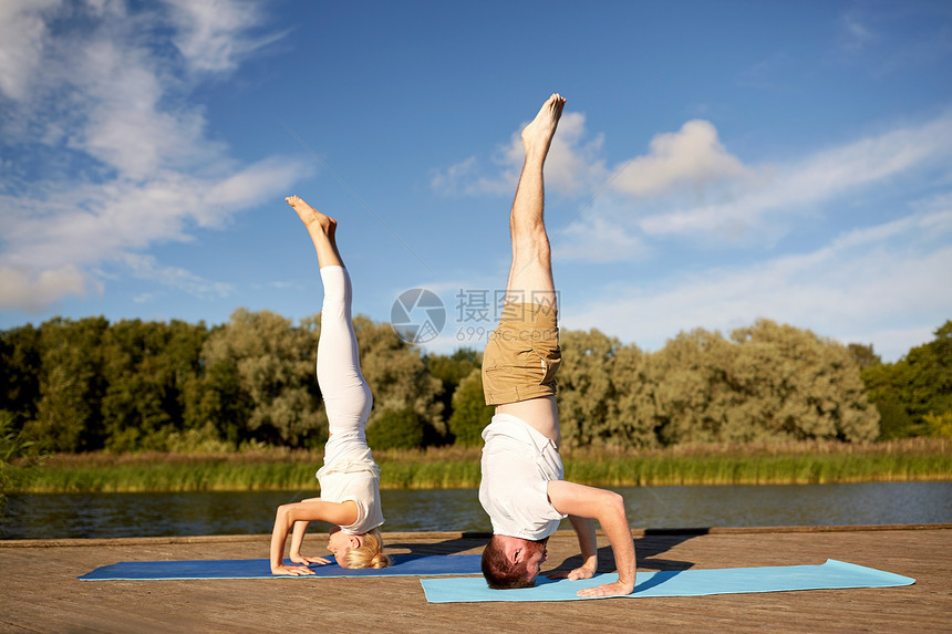 健身,运动,瑜伽,人健康的生活方式夫妇头倒立姿势垫子上的河流湖泊泊位夫妇户外垫子上瑜伽倒立图片