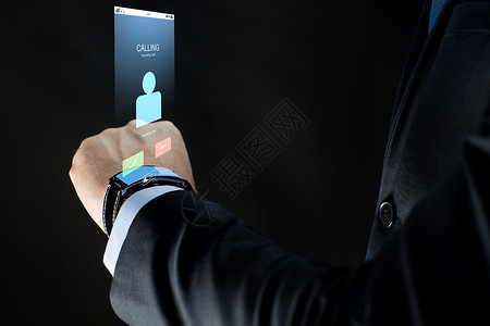 手腕表商业,人,通信技术密切的商人手与智能手表来电虚拟投影黑色背景用智能手表商人的手设计图片