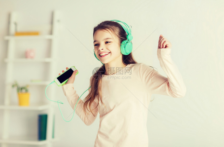 人们,孩子,睡衣派技术快乐的微笑女孩戴着耳机,带着智能手机,家听音乐家里智能手机耳机的女孩图片