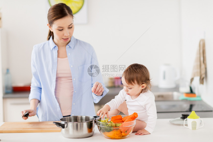 家庭,食物,健康饮食,烹饪人的快乐的母亲小女婴与蔬菜锅家里厨房快乐的母亲婴儿家厨房饭图片