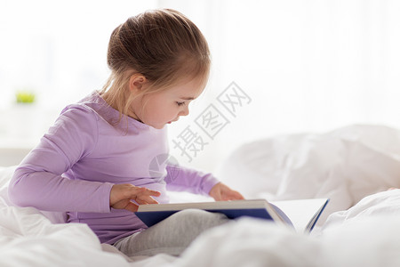 人,童睡前的快乐的小女孩家床上看书快乐的小女孩家床上看书图片
