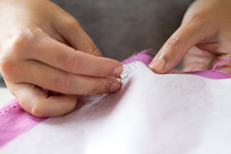 人,针线活裁剪裁缝妇女与针缝纸图案物缝纫工作室女人用别针把纸图案缝布料上背景图片