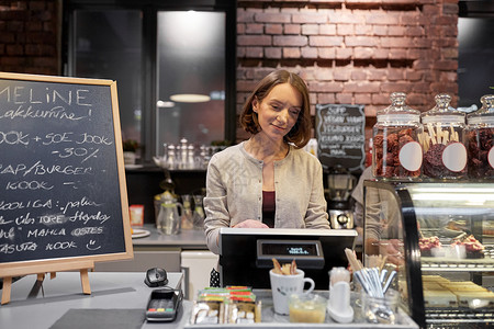 小企业,人服务理念快乐的女人酒吧服务员柜台与现金箱工作咖啡馆咖啡店咖啡馆里带着现金箱的快乐女人酒吧服务员餐厅高清图片素材