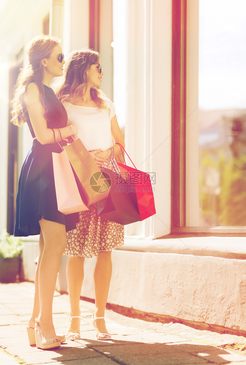 销售,消费主义人的快乐的轻妇女带着购物袋看着城市的商店橱窗快乐的女人商店橱窗里着购物袋图片