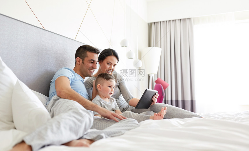 人,家庭技术的快乐的母亲,父亲小男孩家里酒店房间的床上用平板电脑电脑家里平板电脑的幸福家庭图片