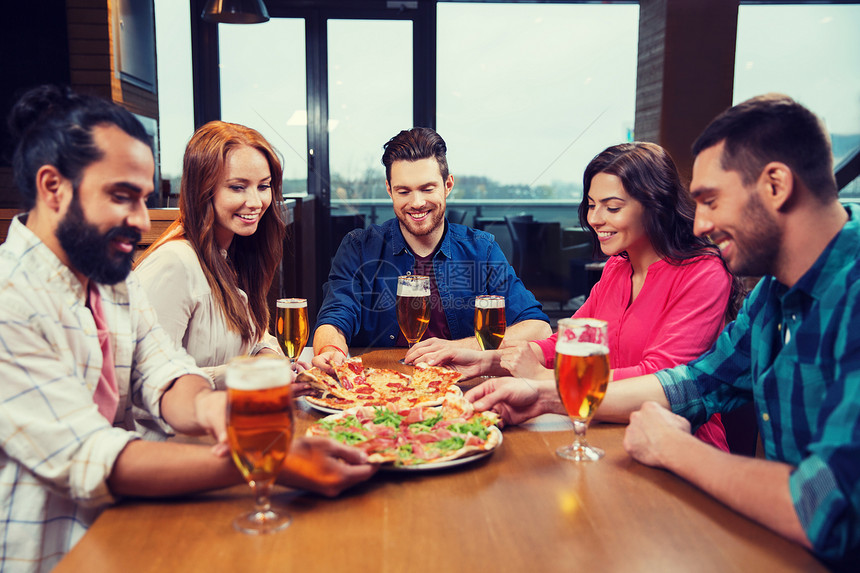 休闲,食物饮料,人假日的微笑的朋友餐馆酒吧吃比萨饼喝啤酒朋友们餐厅用啤酒吃比萨饼图片