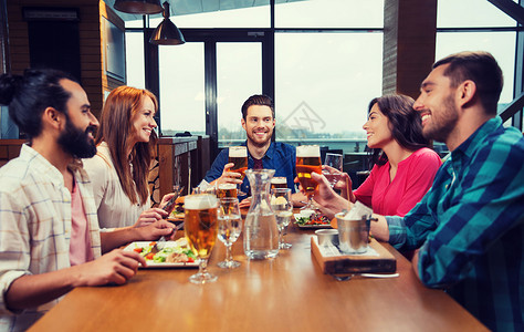休闲,饮食,食物饮料,人假日的微笑的朋友餐馆酒吧吃晚餐喝啤酒朋友们餐馆吃饭喝啤酒背景图片