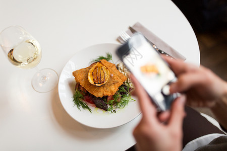 破碎照片食物,新北欧美食,技术,饮食人的女人与智能手机拍摄包鱼片与酒石酱烤箱烤甜菜根番茄沙拉餐厅智能手机的女人咖啡背景