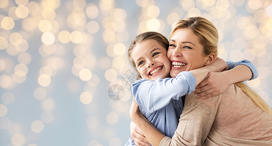 人家庭的快乐的微笑女孩与母亲拥抱节日的灯光背景快乐的女孩母亲拥抱灯光外国小孩高清图片素材