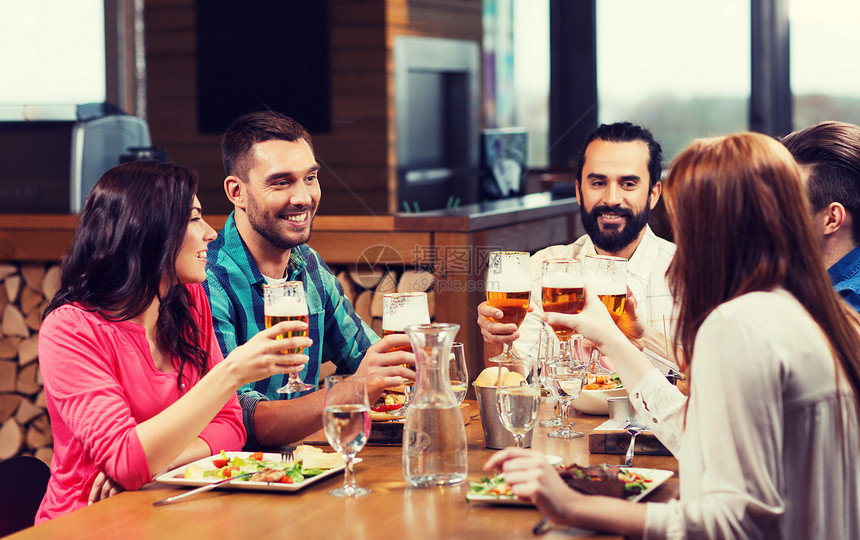 休闲,饮食,食物饮料,人假日的微笑的朋友餐馆酒吧吃晚餐喝啤酒朋友们餐馆吃饭喝啤酒图片
