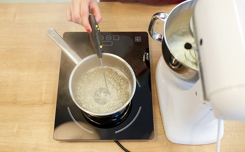 烹饪,食品厨房用具的电动搅拌机炉子上的锅厨师厨房测量糖浆中的温度图片