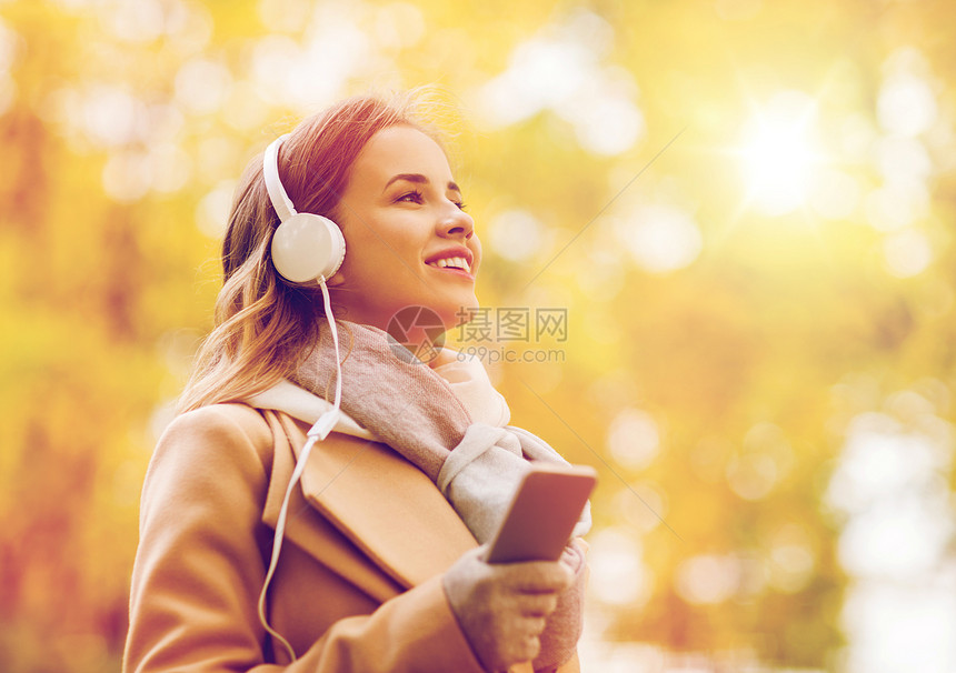季节,技术人的美丽的快乐轻女子戴着耳机,智能手机上听音乐,秋天的公园散步秋天公园里智能手机耳机的女人图片