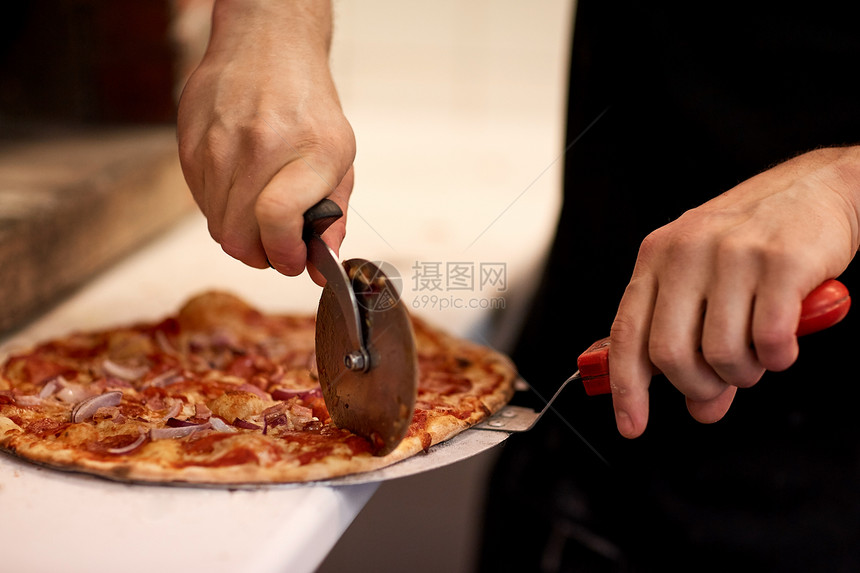 食物,意大利厨房烹饪比萨饼店用切割机切割比萨饼比萨饼店把比萨饼切成碎片图片