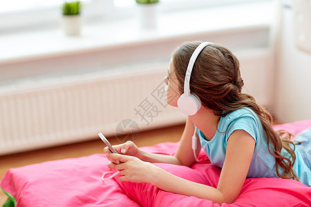 人,孩子,技术休闲女孩戴着耳机躺床上,家听音乐戴耳机的女孩家听音乐图片
