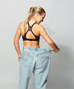 健身,饮食,减肥人的轻的苗条运动妇女穿着超大的裤子穿着超大裤子的轻苗条运动女人背景图片