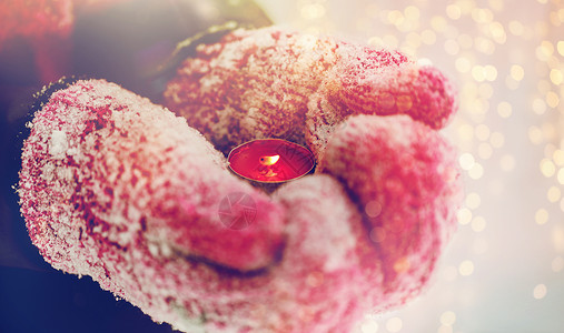 寒假诞节人们的把手放手套里,户外着燃烧的茶烛冬天的手套里,紧握着蜡烛图片