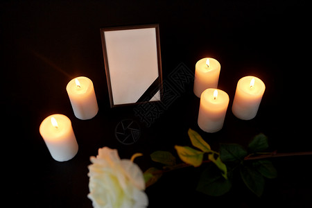 葬礼哀悼相框与黑色丝带,花燃烧蜡烛黑暗中带黑色丝带花蜡烛的相框背景图片