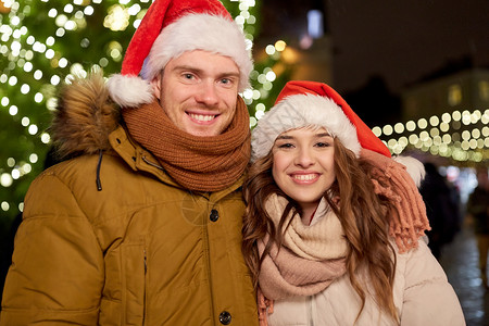 寒假人们的快乐的轻夫妇戴着诞帽诞树晚上诞树上戴着诞老人帽子的幸福夫妇背景图片
