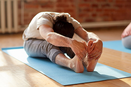 健身,运动健康的生活方式男人瑜伽,坐前弯姿势垫子上工作室健身房工作室健身房瑜伽前弯的人背景图片