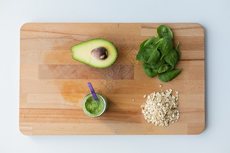 婴儿食品,健康饮食营养璃罐与绿色蔬菜泥燕麦片木制切割板木板上果泥婴儿食品的罐子背景图片