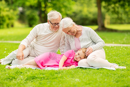 家庭世代人的快乐的微笑祖母,祖父小孙女公园的毯子上休息公园的祖父母孙女图片