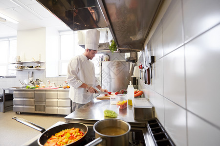 烹饪食物,职业人的男厨师用刀切西红柿餐厅厨房的砧板上饭餐厅厨房的男厨师烹饪食物背景图片