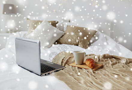 舒适的家,室内冬季舒适的卧室与笔记本电脑,咖啡杯牛角包家里的床上雪笔记本电脑,咖啡牛角包床上舒适的家背景图片
