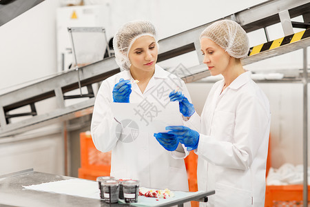 食品生产,工业人的妇女技术人员与剪贴板品尝冰淇淋质量工厂女技术人员工厂品尝冰淇淋背景图片