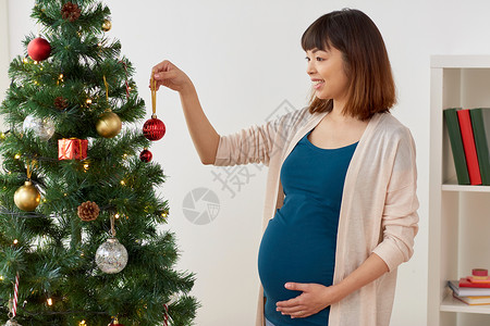 怀孕,寒假人们的怀孕的亚洲妇女家里装饰诞树孕妇家装饰诞树背景图片