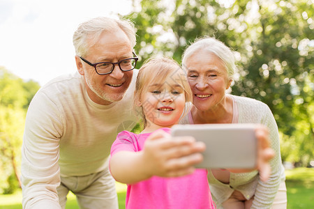 祖母照片素材快乐的祖父母孙女公园用智能手机自拍背景
