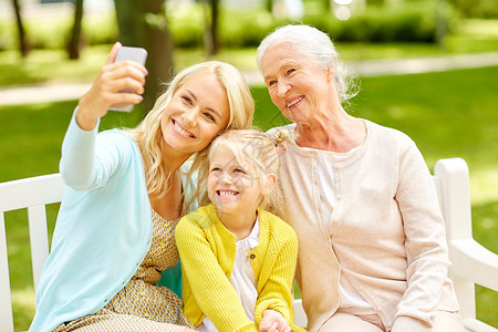 祖母照片素材家庭世代人的快乐的微笑母亲与女儿祖母公园用智能手机自拍母亲带着女儿祖母公园背景