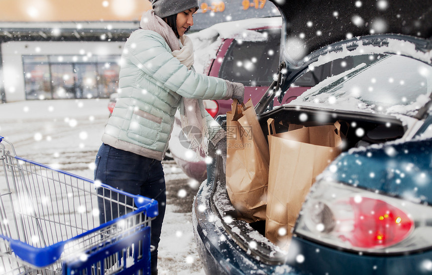 消费主义,交通人的女顾客冬天的雪地停车时购物车汽车后备箱装载食物顾客把食物购物车运汽车图片