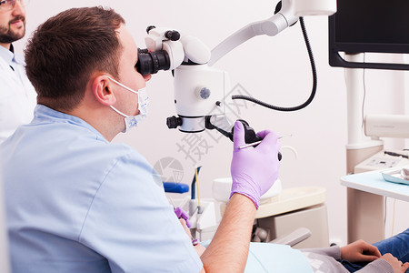 牙医透过放大镜看他牙科办公室用显微镜手术背景图片
