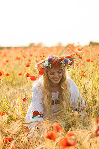 漂亮的金发女孩穿着件图案的花的连衣裙,头上戴着花环,片花的田野里享受着田里的女孩图片