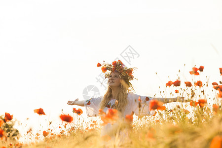 漂亮的金发女孩穿着件图案的花的连衣裙,头上戴着花环,片花的田野里享受着田里的女孩图片