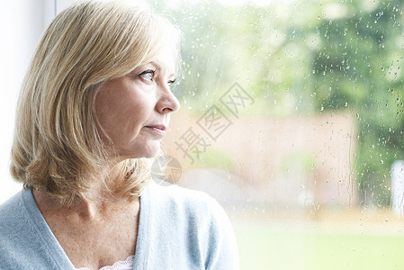 悲伤成熟的女人患广场惧症,望着窗外背景图片
