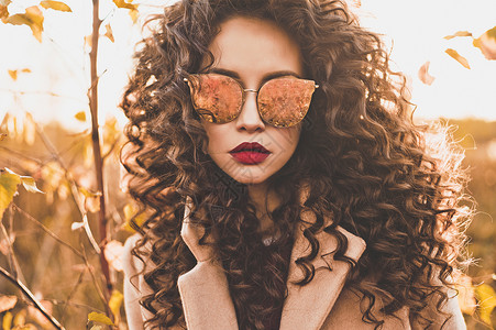 户外时尚照片,轻美丽的女士戴着太阳镜包围秋叶时尚看书温暖的秋天秋天的气氛温暖的冬天背景图片